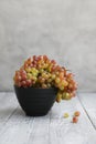 Still life with colored grapes in a black bowl on a gray wooden table Royalty Free Stock Photo