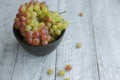 Still life with colored grapes in a bowl on a gray wooden table in day light Royalty Free Stock Photo