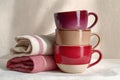 Still life composition featuring three ceramic cups stacked in a harmonious three-tone palette alongside soft fabrics Royalty Free Stock Photo