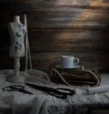 Still-life with a cup of coffee, scissors, mannequin sewing and lace on a background of rough wooden walls. vintage Royalty Free Stock Photo