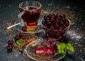 Still life with a Cup of strong tea, ripe cherries and cherry cake on a black background Royalty Free Stock Photo