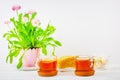 Still life with cups of tea, pieces of cake, a bouquet of pink flowers in a pink pot and marshmallows on a white wooden table Royalty Free Stock Photo