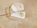 Still life of a delicate gold chain necklace with gold shell and turquoise bead