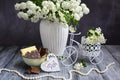 Still life details, bowl with chocolate and decorative bike with flowers, white beads and a wooden heart on a gray rustic
