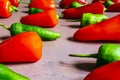 A still life with a dirty pink surface with many crisscrossed green and red peppers