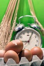 Still life with eggshells and eggs, old broken alarm clock, paddy rice seed, green background. Royalty Free Stock Photo