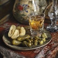 Still life featuring a drink in a glass, assorted pickles, and a backdrop of a decorative vase Royalty Free Stock Photo