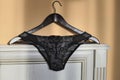 Still-life of female black underwear on a wooden hanger, on a fragment of a wooden classic headboard