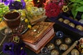 Still life with flowers, magic book of spells, cups on witch ritual table.