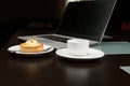 A sweet delicious tartlet with lemon custard, a cup of freshly brewed espresso coffee over the background of a laptop