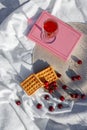 Still life and food photo. Cherry and waffle berries lie on a wicker round napkin and crumpled fabric