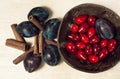 Still life food with plums, red berries and cinnamon sticks in a