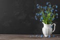 Still life with forget me not flowers bouquet in vase on dark background with copy space. festive background