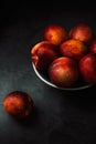 Still life of fresh nectarines with droplets of water in a bowl on dark background. Low key Royalty Free Stock Photo