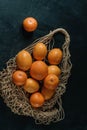 Still life with fresh lemons in a cotton string bag on a black .