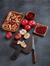 Still life with fresh lingonberries, red appples with knife on black cutting board and homemade jam on dark background. Top view