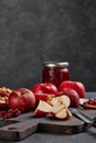 Still life with fresh lingonberries, red appples with knife on black cutting board and jar of homemade jam on dark background Royalty Free Stock Photo