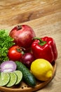 Still life of fresh organic vegetables on wooden plate over wooden background, selective focus, close-up Royalty Free Stock Photo