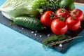 Still life of fresh organic vegetables on wooden plate over blue background, selective focus, close-up Royalty Free Stock Photo