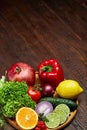 Still life of fresh organic vegetables on wooden plate over wooden background, selective focus, close-up Royalty Free Stock Photo