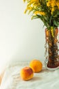 Still life with fresh peaches on linen cloth background on wooden table. Bright juicy summer fruits with yellow flowers