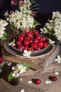 Still life with fresh red cherries with water drops and jasmine flowers on a ceramic plate on a vintage wooden background Royalty Free Stock Photo