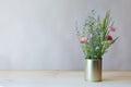 Still life fresh tender fragile beautiful wildflowers and green grass in metal can on wooden table on gray background