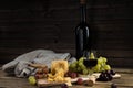 Still life from fruit, cheese and wine. The piece of hard cheese lies on a chopping board. Clusters of red and green mature grapes