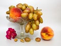 Still life with fruit peaches and grapes on a glass vase on a grey or silver background. Royalty Free Stock Photo