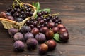 Still life of fruits. Bunch of grapes in wicker basket. Figs and plums on table Royalty Free Stock Photo