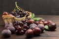 Still life of fruits. Bunch of grapes in wicker basket. Figs and plums on table Royalty Free Stock Photo