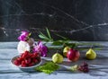 Still life of fruits: pears, apple, a plate with strawberries, lettuce leaves and fresh peony flowers on a dark marble background Royalty Free Stock Photo