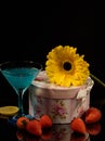 Still-life. Gift box, flower, cocktail glass, strawberry on a dark background