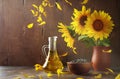 Still life of glass bottle with sunflower oil, seeds and flowers in ceramic vase Royalty Free Stock Photo