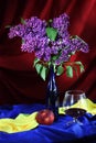 Still-life with glass of red wine, juicy apple and lilac in vase Royalty Free Stock Photo