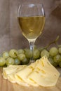 Still life with glass of white wine, cheese and grapes Royalty Free Stock Photo