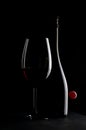 Elegant red wine glass and a wine bottle with red cherry isolated on the black background. bottle silhouette Royalty Free Stock Photo