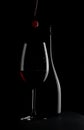 Elegant red wine glass and a wine bottle with red cherry isolated on the black background. bottle silhouette Royalty Free Stock Photo