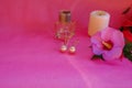 Still life with golden earrings with pearls, white candle, bottle with perfume, pink flower on pink background. Copy space. Elegan Royalty Free Stock Photo