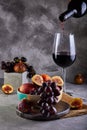 Still life of grapes, peaches, figs and glasses of red wine on a gray