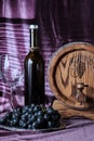 Still life of grapes and wine. Wooden barrel, berries and bottle on a purple background. Selective focus