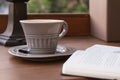 Still life with a gray ceramic cup of coffee on a saucer and an open diary with a pen Royalty Free Stock Photo