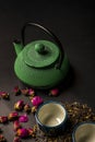 Still life with a green cast-iron teapot, two Japanese porcelain cups with tea scattered between them and dried rosebuds on a Royalty Free Stock Photo