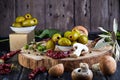 Still life of green fresh olives, red pepper and fresh mushrooms with olive tree leaves on a dark wooden Royalty Free Stock Photo