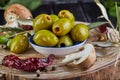 Still life of green fresh olives, red pepper and fresh mushrooms with olive tree leaves on a dark wooden close up Royalty Free Stock Photo