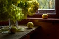 Still life with green hydrangea flowers and three green apples by window of a wooden country house