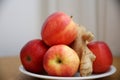 Still life of a group of apples and ginger roots on a white stand