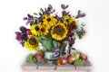 A spectacular bouquet of sunflowers in a vase and apples, grapes. Royalty Free Stock Photo