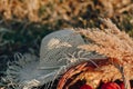 Still life with hat, bouquet, fruit in a basket in a field on hay. sunny summer weather