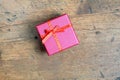 Still life with holiday gift in small red color box, covered with ribbon with bow on wooden background top view Royalty Free Stock Photo